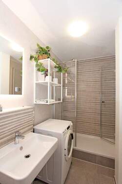 Badezimmer mit Badewanne, Dusche, WC sowie Waschmaschine - 