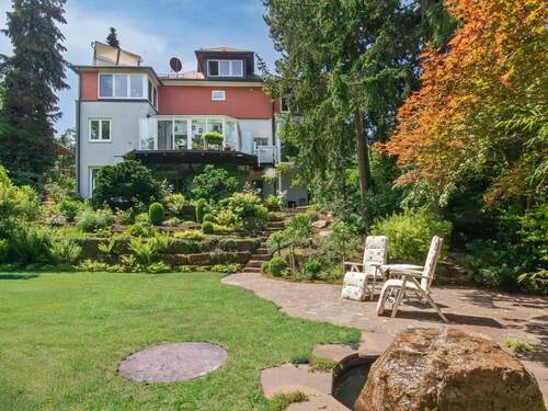 Hausansicht vom unteren Garten aus mit Terrasse und Brunnen - Freistehendes Einfamilienhaus mit persönlichem Gartentraum
