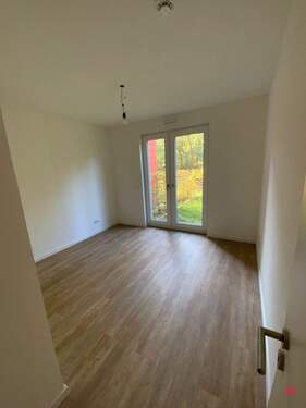 Zimmer mit weißen Wänden und holzfarbenen Vinylboden - 