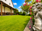 Rosenpracht und Gartenfigur als liebevolle Details im Garten.png - 