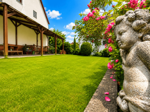 Rosenpracht und Gartenfigur als liebevolle Details im Garten.png - 