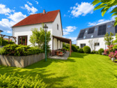 Sonniger Garten mit Terrasse und Blick auf das Haus.png - 