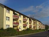Rückansicht auf das gelb gestrichene Haus mit roten Balkonen. - Gemütliche 2,5-Zimmer Wohnung mit Balkon in Rodgau!