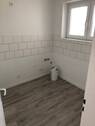 Blick von Diele in Küche mit weißen Fliesenspiegel, grauem PVC -Boden und tapezierfähigen Wänden mit weißen Fenstern - 2 Zimmer Etagenwohnung in Neuss