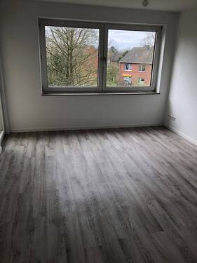 Blick von Diele in Wohnzimmer mit grauen PVC-Boden und tapezierfähigen Wänden mit weißen Fenstern und Tür zu Balkon - Etagenwohnung mit 51,30 m&sup2; in Neuss zur Miete