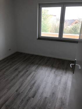 Blick in Schlafzimmer mit grauen PVC-Boden und tapezierfähigen Wänden mit weißen Fenstern - 