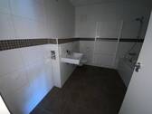 Blick in Bad mit weißen Wandfliesen, braunen Bodenfliesen Hänge-WC - 