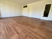  Blick von in Wohnraum mit braunem PVC-Boden und weißen Wänden - 