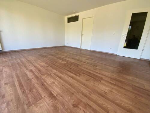  Blick von in Wohnraum mit braunem PVC-Boden und weißen Wänden - 