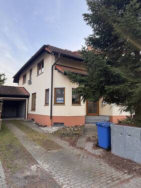 Gepflegter Hauseingang mit befestigtem Zugangsweg und integrierter Garage - 