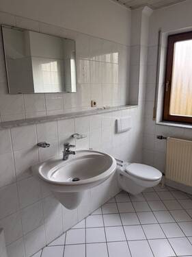 Praktisches Badezimmer mit Wandspiegel und zeitgemäßer Sanitärausstattung - 