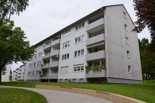 Akazienallee 12, Außenansicht vom Gehweg auf die helle Fassade eines mehrgeschossigen Wohngebäudes (Riegel) mit Satteldach - Ideal für Familien: 4-Zimmerwohnung mit Balkon in Baunatal-Baunsberg