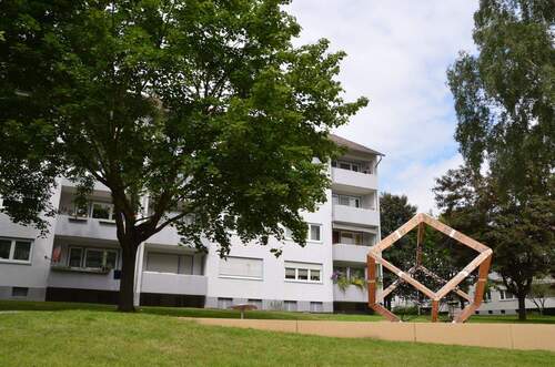Akazienallee 12, Außenansicht mit Blick über Spielplatz mit Kletterwürfel auf Balkonseite - 4 Zimmer Etagenwohnung in Baunatal