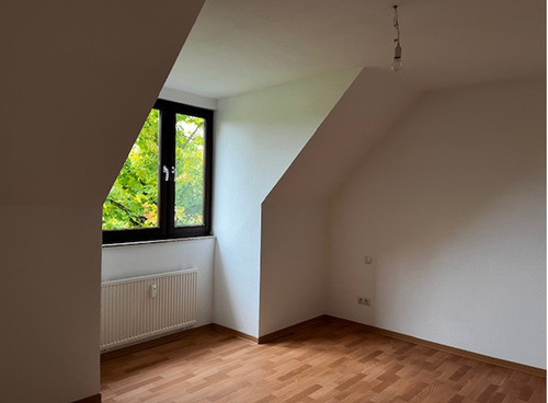 Schlafzimmer mit hellen Wänden und holzfarbenem Bodenbelag, leichte Dachschräge im Fensterbereich..PNG - 2 Zimmer Etagenwohnung in Baunatal