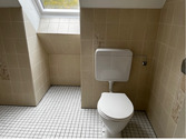 Tageslichtbad mit hellbrauner Wandverfliesung und weißen Bodenfliesen, leichte Dachschräge im Fensterbereich.PNG - Etagenwohnung mit 67,10 m² in Baunatal zur Miete