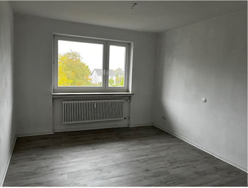 Wohn- und Essbereich mit Blick zu Fensterfront und Zugang zum Balkon, heller Bodenbelag und helle Wände.PNG - 
