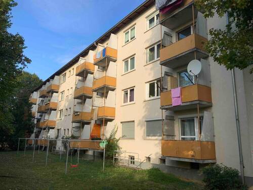 Außenansicht des mehrstöckigen Wohngebäudes mit Balkonen umgeben von Bäumen - 2-ZKB-Wohnung in Frankfurt-Hausen sucht neue Bewohner!