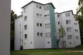 Seitenansicht eines mehrstöckigen Wohngebäudes mit Balkonen, umgeben von Bäumen und grünen Sträuchern - Schicke-3-Zimmer-Wohnung - 531,00&nbsp;EUR Kaltmiete, ca.&nbsp; 66,00&nbsp;m&sup2;&nbsp;Wohnfl&auml;che