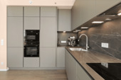 Maßgefertigte Designküche mit integrierten Miele-Geräten und Natursteinoberflächen - 