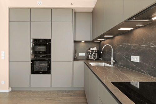 Maßgefertigte Designküche mit integrierten Miele-Geräten und Natursteinoberflächen - 