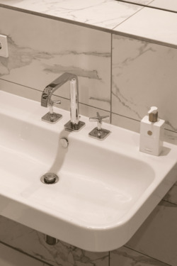 Duravit-Waschtisch mit verchromter Drei-Loch-Armatur vor weißem Marmordekor - 