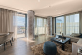 Weitläufiges Wohnzimmer mit Zugang zum Balkon und urbanem Ausblick - 