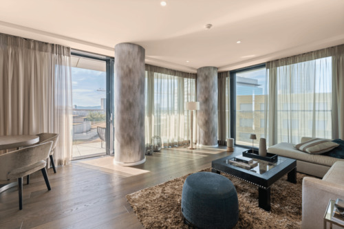 Weitläufiges Wohnzimmer mit Zugang zum Balkon und urbanem Ausblick - 
