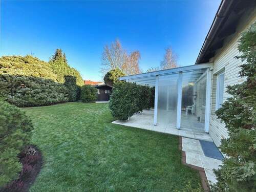 Blick in den Garten auf der Nordseite des Hauses mit überdachter Terrasse und einem Gartenhaus - 
