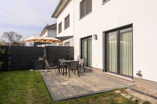 Terrasse mit Sitzgelegenheit und aufgespanntem Sonneschirm - 
