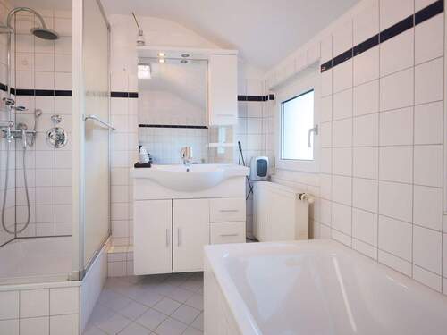 Hell gefliestes Tageslichtbadezimmer mit Badewanne und Dusche - 