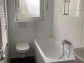 Badezimmer mit weißer Badewanne, hängenden WC, Waschbecken und Fenster. Bodenfliesen in anthrazit. - 2 Zimmer Etagenwohnung zur Miete in Frankfurt am Main