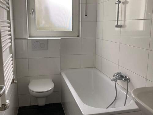 Badezimmer mit weißer Badewanne, hängenden WC, Waschbecken und Fenster. Bodenfliesen in anthrazit. - 2 Zimmer Etagenwohnung zur Miete in Frankfurt am Main