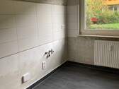 Küche mit weißem Fliesenspiegel, Heizkörper und anthrazitfarbenen Bodenfliesen. - 2 Zimmer Etagenwohnung in Frankfurt am Main