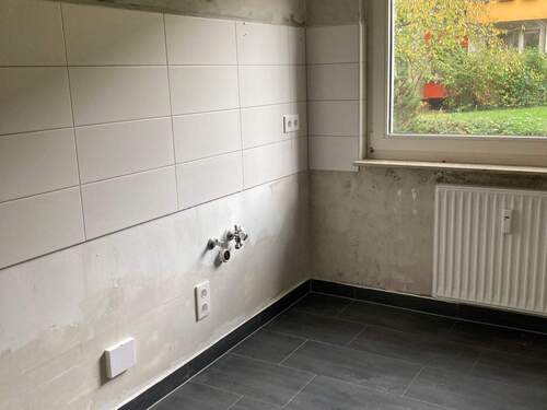 Küche mit weißem Fliesenspiegel, Heizkörper und anthrazitfarbenen Bodenfliesen. - 2 Zimmer Etagenwohnung in Frankfurt am Main