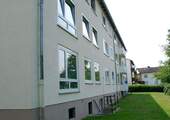 Rückansicht auf das Mehrfamilienhaus mit einer Rasenfläche und großen Fenstern - Schöne 2-Zimmer Wohnung mit neuen Bodenbelägen und Balkon zu vermieten