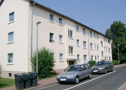 Vorderansicht auf das dreistöckige Mehrfamilienhaus mit einem Parkstreifen und Sträuchern vor der Tür - 2 Zimmer Etagenwohnung zur Miete in Bad Hersfeld