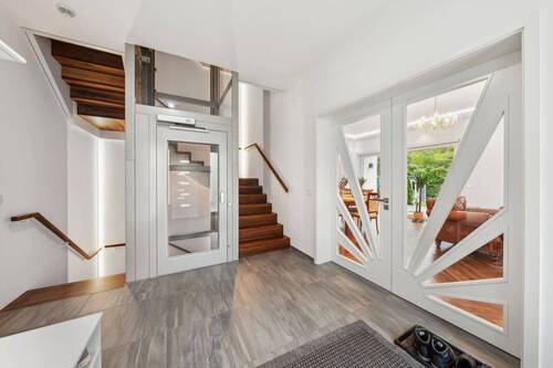 Großzügiges Entrée mit gläsernem St.Gobain Lift und maßgefertigter Flügeltür aus lackierter Buche mit Glaseinsätzen - 