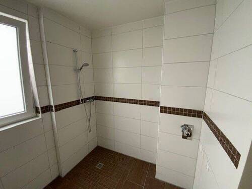 Blick in Bad mit weißen Wandfliesen, braunen Bodenfliesen Hänge-WC und bodengleiche Dusche - Etagenwohnung mit 86,00 m&sup2; in Meerbusch zur Miete