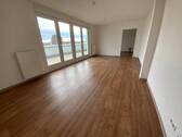 Blick von in Wohnraum mit braunem PVC-Boden und weißen Wänden mit weißen ebenerdigen Fenstern und weißer Balkontür - 