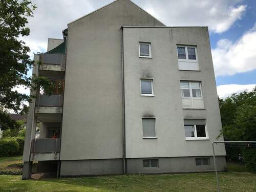 Lindenallee 19: Blick über die Außenanlage auf die Giebelseite eines Gebäudes mit kombiniertem Sattel- und Flachdach. - 3 Zimmer Etagenwohnung zur Miete in Baunatal