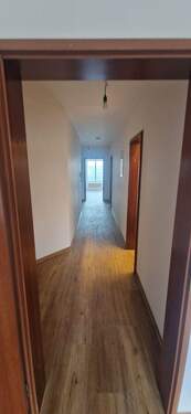 Rückansicht eines mehrstöckigen Wohngebäudes mit Garagen und Stellplätzen, umgeben von Bäumen und grünen Hecken. - 2 Zimmer Etagenwohnung zur Miete in Frankfurt am Main