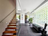 Der Empfangsbereich präsentiert sich lichtdurchflutet; die freitragende Treppe setzt die Transparenz der Fensterflächen elegant fort - 