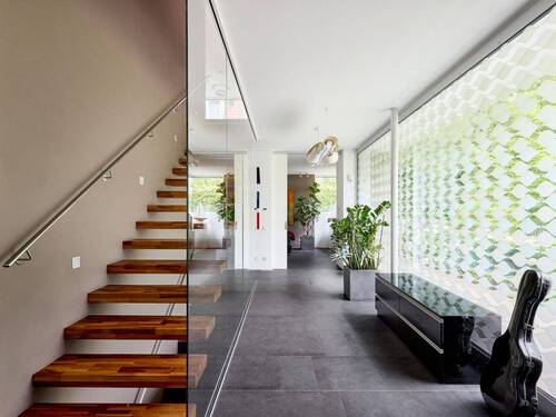 Der Empfangsbereich präsentiert sich lichtdurchflutet; die freitragende Treppe setzt die Transparenz der Fensterflächen elegant fort - 