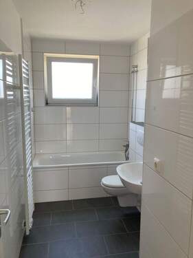 Bad mit Fenster, weißen Sanitärobjekten, Handtuchheizkörper, weißen Wandfliesen und Bodenfliesen in anthrazit - Nachmieter für 2-Zimmerwohnung gesucht!