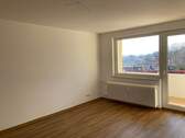 Wohnzimmer mit Zugang zum Balkon und hochwertigem Vinylbelag in Holzoptik - 2 Zimmer Etagenwohnung in Friedrichsdorf