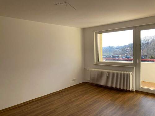 Wohnzimmer mit Zugang zum Balkon und hochwertigem Vinylbelag in Holzoptik - 2 Zimmer Etagenwohnung in Friedrichsdorf