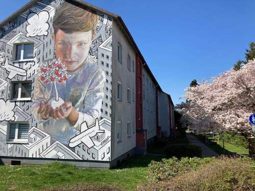 Gebäudeansicht im Frühling mit blühenden Bäumen - Kleine, gemütliche Wohnung in zentraler Lage sucht Nachmieterin