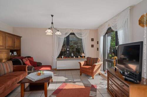 Wohnbereich mit Fliesenboden und großem Fenster zur Terrasse und schönem Gartenblick. - 