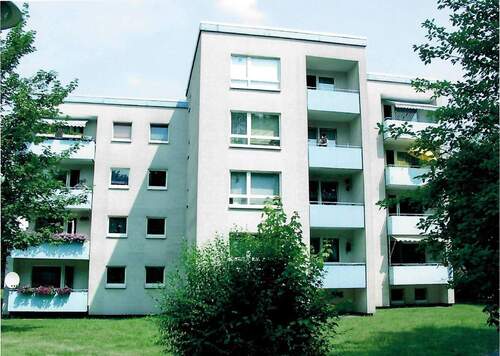 An der Baun 10, Außenansicht über die Grünanlage mit altem Baumbestand auf die farbig abgesetzten Balkone eines mehrgeschossigen Wohngebäudes.JPG - Familien willkommen: 4-ZImmerwohnung in zentraler Lage von Altenbauna