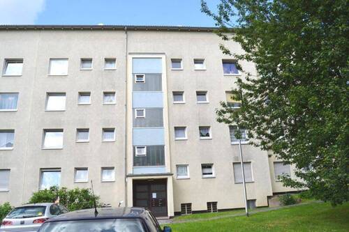  Vorderansicht eines mehrstöckigen Wohngebäudes , umgeben von Bäumen und grünen Sträuchern - 3 Zimmer Etagenwohnung zur Miete in Kassel
